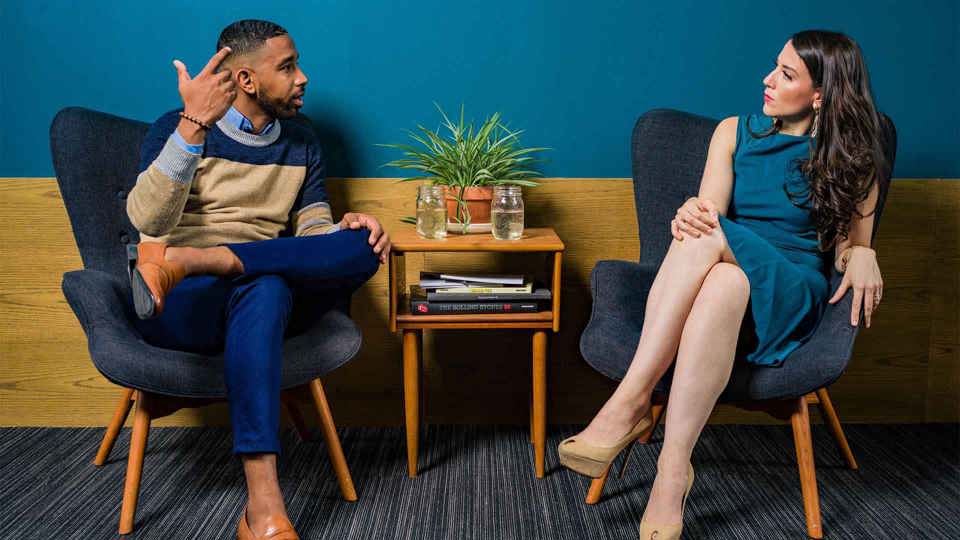 Two persons sitting on chairs and talking